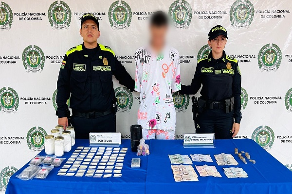 Dos Policías, una persona capturada y mesa con estupefacientes