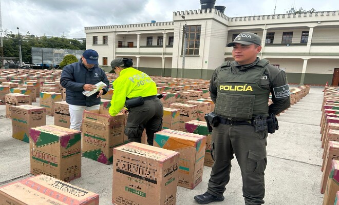 dos Polic&iacute;as revisando incautaci&oacute;n de cajas las cuales contienen cigarrillos y un polic&iacute;a custodiando 