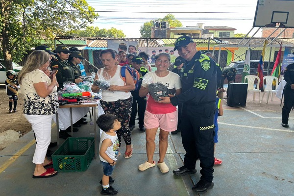 Un Policía de infancia y adolescencia haciendo entrega de articulo a una ciudadana durante el desarrollo de la actividad