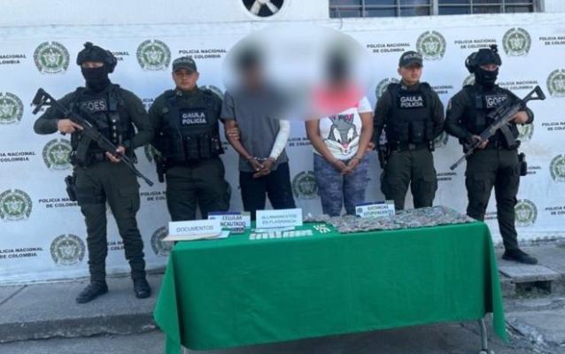 la polic&iacute;a nacional al lado de dos hombres capturados con estupefacientes