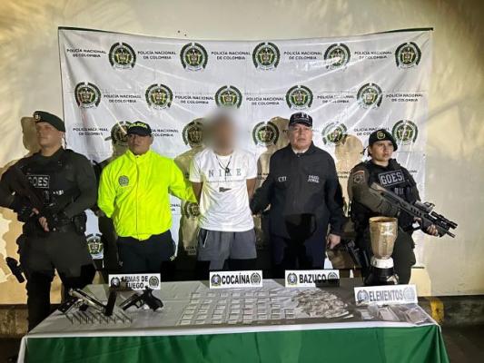 la policía nacional el CTI al lado de un hombre capturado con elementos incautados