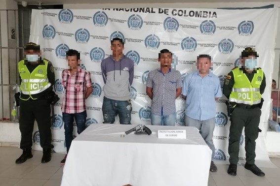 4 personas capturadas-policías custodiando-arma de fuego incautada 