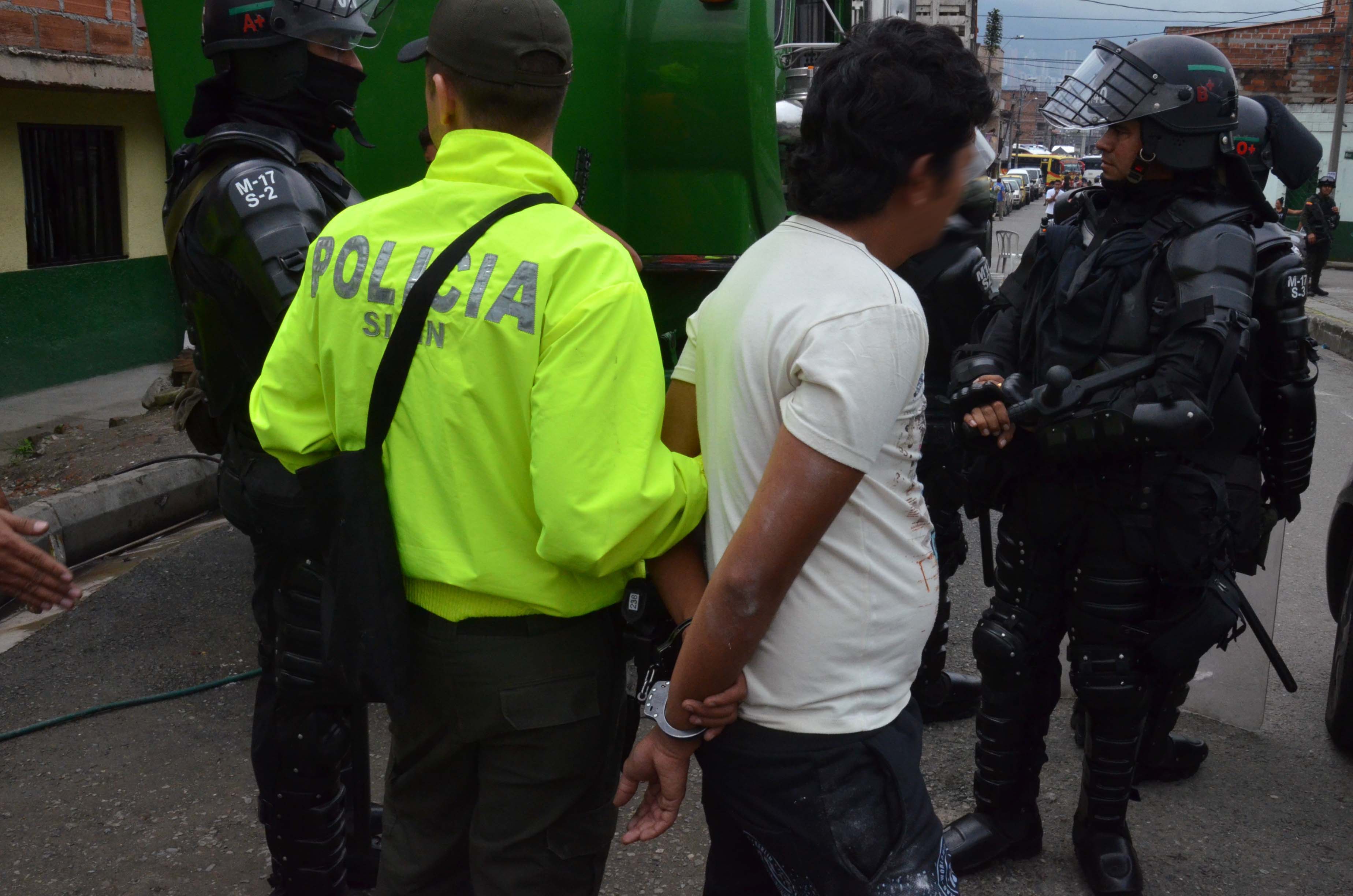 Policía de la Sijin conduce a un hombre esposado