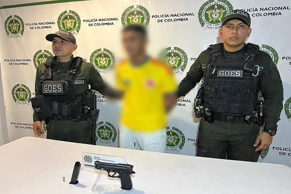 Dos policías presentan a un capturado junto a un arma de fuego incautada