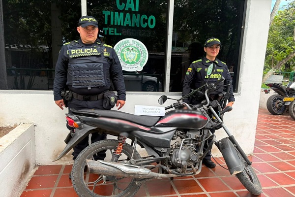 Dos funcionarios de la Policía junto a una motocicleta recuperada