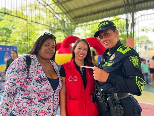 una mujer policía junto a dos ciudadanas mirando hacia la cámara