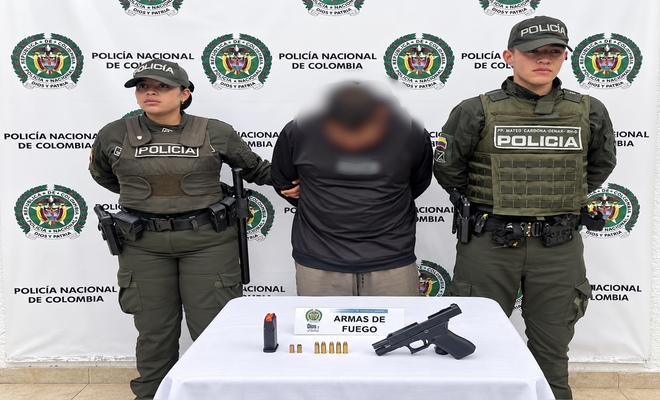 Un ciudadano capturado, esposado y con dos uniformados de la Policía en cada lado, así como un arma de fuego incautada