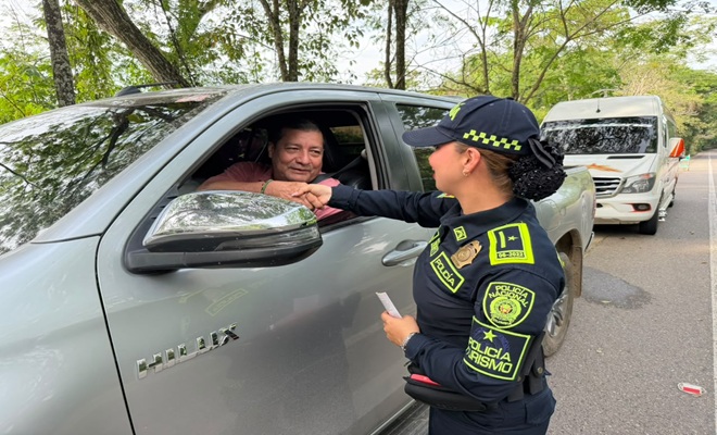 Uniformada de la Policía Nacional brindando recomendaciones preventivas a un ciudadano que va transitando en su vehículo. 