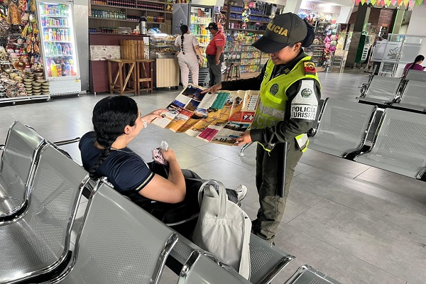 Policía de turismo realizando socialización a una ciudadana en el terminal de transporte