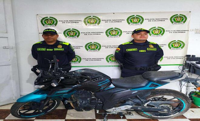 Dos policias junto con una motocicleta 