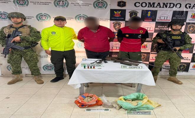 Dos personas capturadas esposadas con material bélico incautado y estupefacientes, asimismo, Policía Judicial y GAULA Militar a sus lados respectivamente