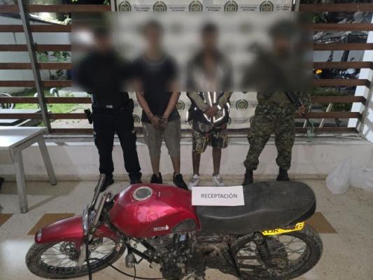 un policía un soldado al lado de un hombre capturado con una motocicleta