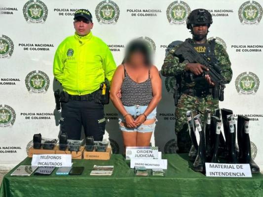 un policía un soldado al lado de una mujer capturada con material incautado