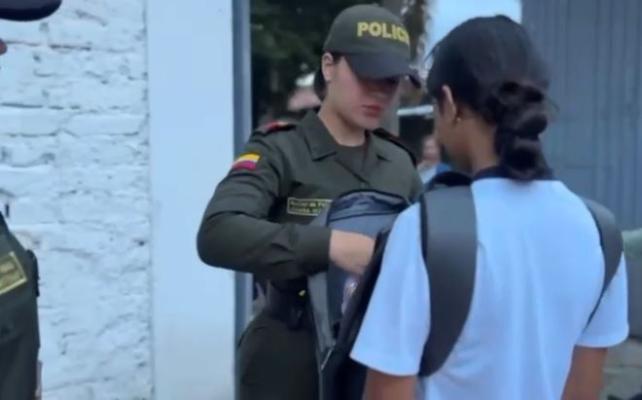 Una auxiliar de policía registrando un bolso a una estudiante