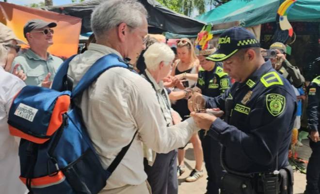 Teniente coronel comandante de seguridad ciudadana con turista entregando un detalle y varias personas a los lados